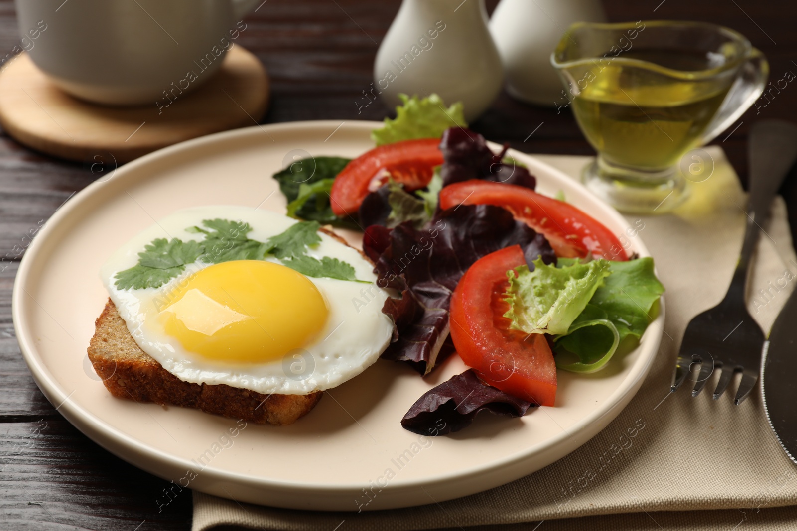 Photo of Delicious breakfast with fried egg and salad served on wooden table, closeup