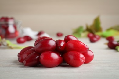 Photo of Pile of fresh ripe dogwood berries on white wooden table, closeup