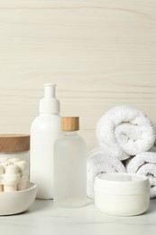 Photo of Different bath accessories and personal care products on white table near light wooden wall