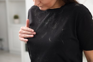 Woman with pet hair on her black clothers indoors, closeup