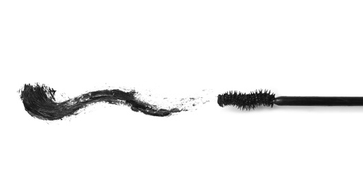 Photo of Applicator and black mascara smear for eyelashes on white background, top view