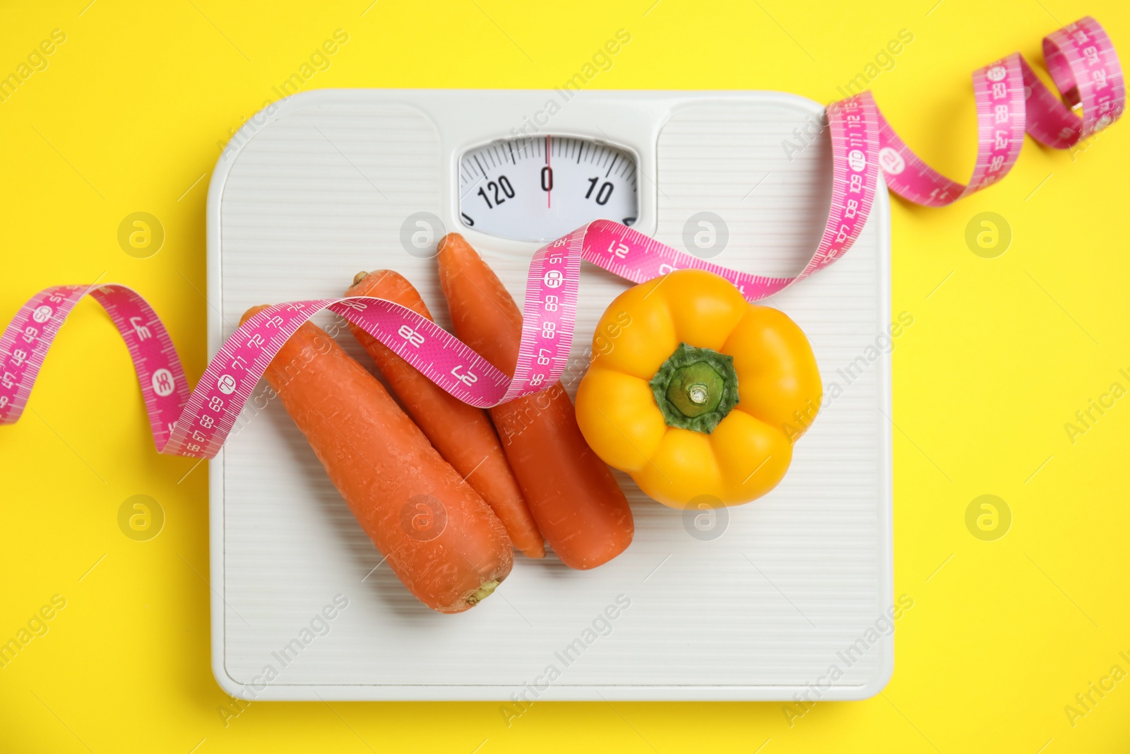 Flat lay composition with scales and vegetables on yellow background Photo of Flat lay composition with scales and vegetables on yellow background