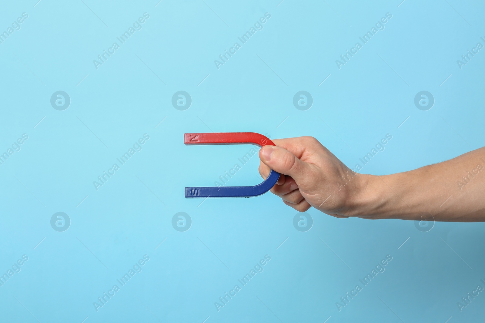 Photo of Man holding magnet on color background, closeup. Space for text