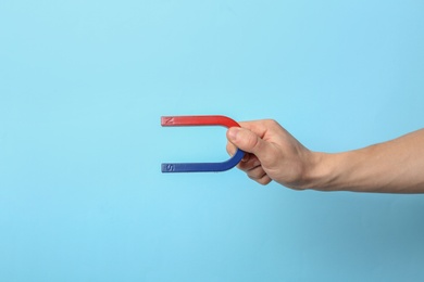 Photo of Man holding magnet on color background, closeup. Space for text