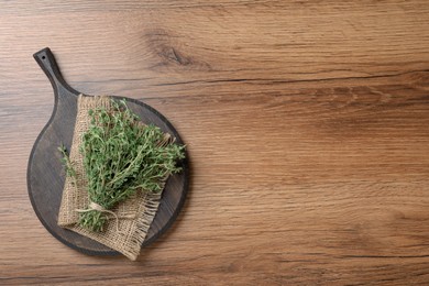 Bunch of aromatic thyme on wooden table, top view. Space for text