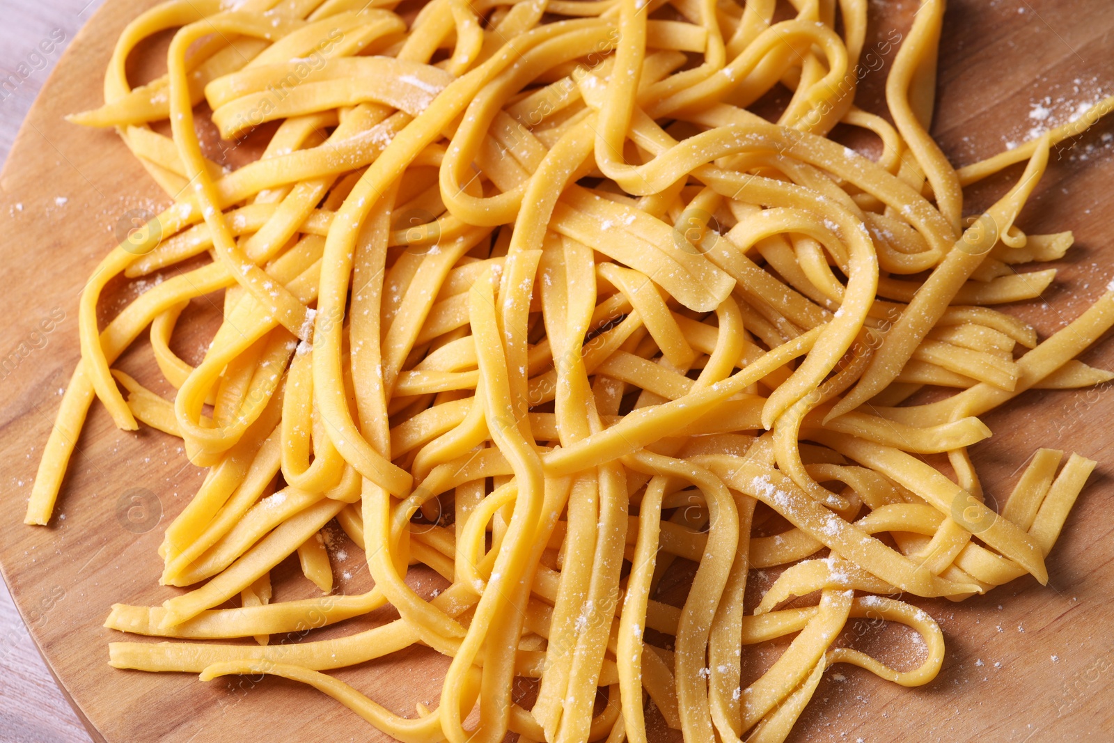 Photo of Raw homemade pasta on wooden board, top view