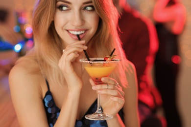 Beautiful young woman with glass of martini cocktail at party