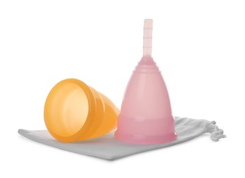 Photo of Menstrual cups with cotton bag isolated on white. Reusable feminine hygiene product