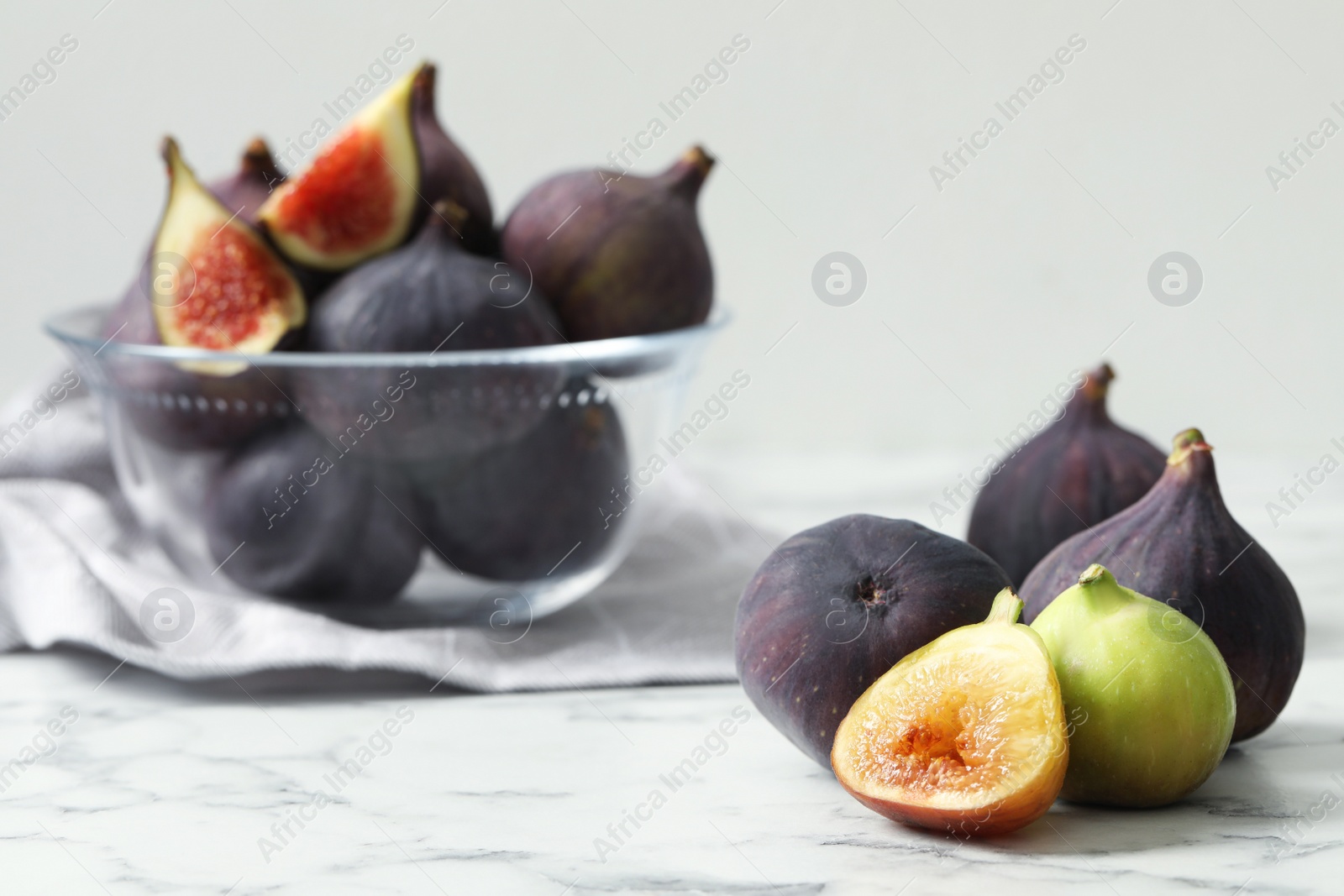 Photo of Tasty fresh purple and green figs on white marble table, space for text