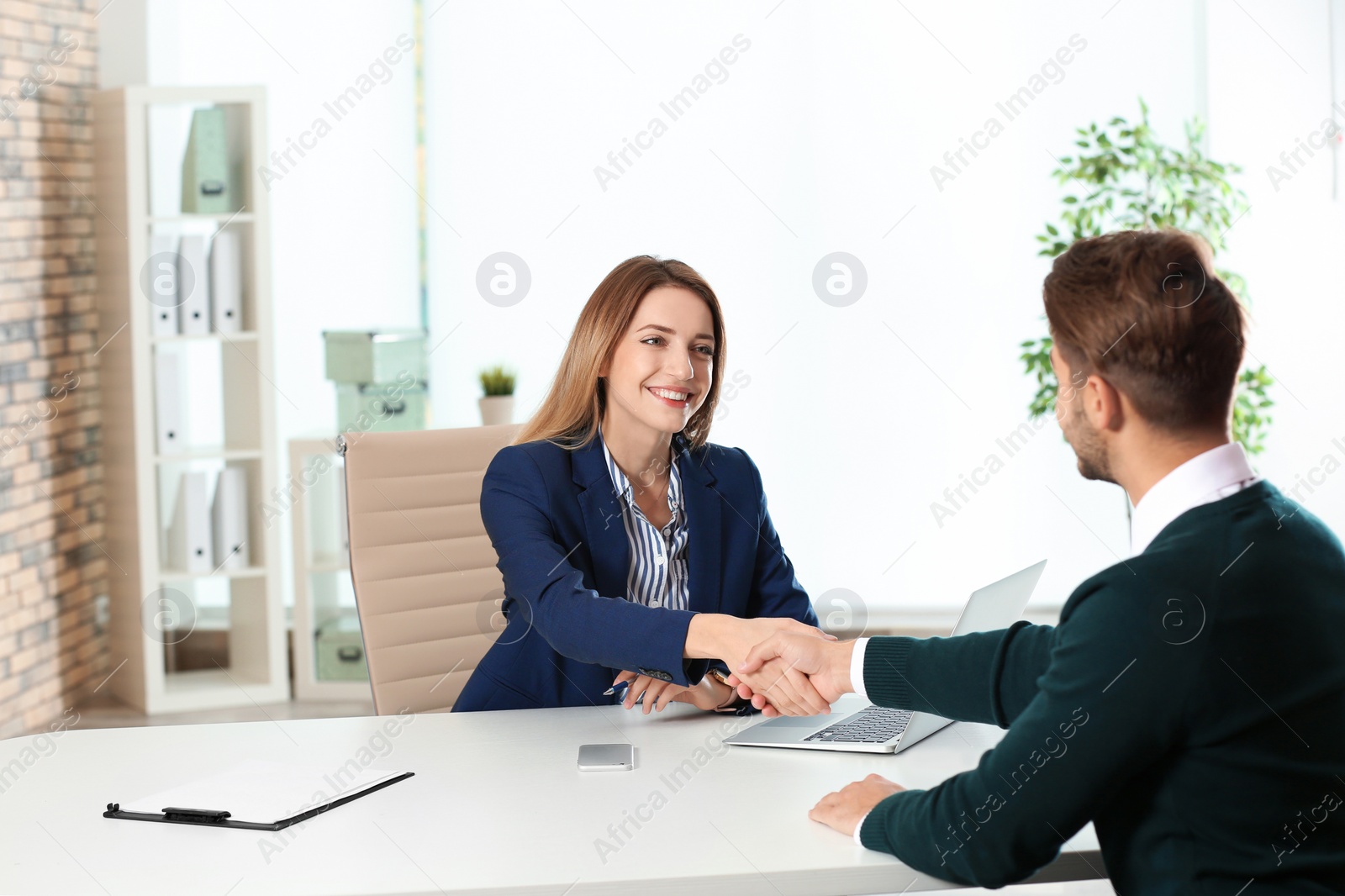 Photo of Human resources manager shaking hands with applicant before job interview in office