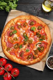 Photo of Delicious pizza Diablo and ingredients on black wooden table, flat lay