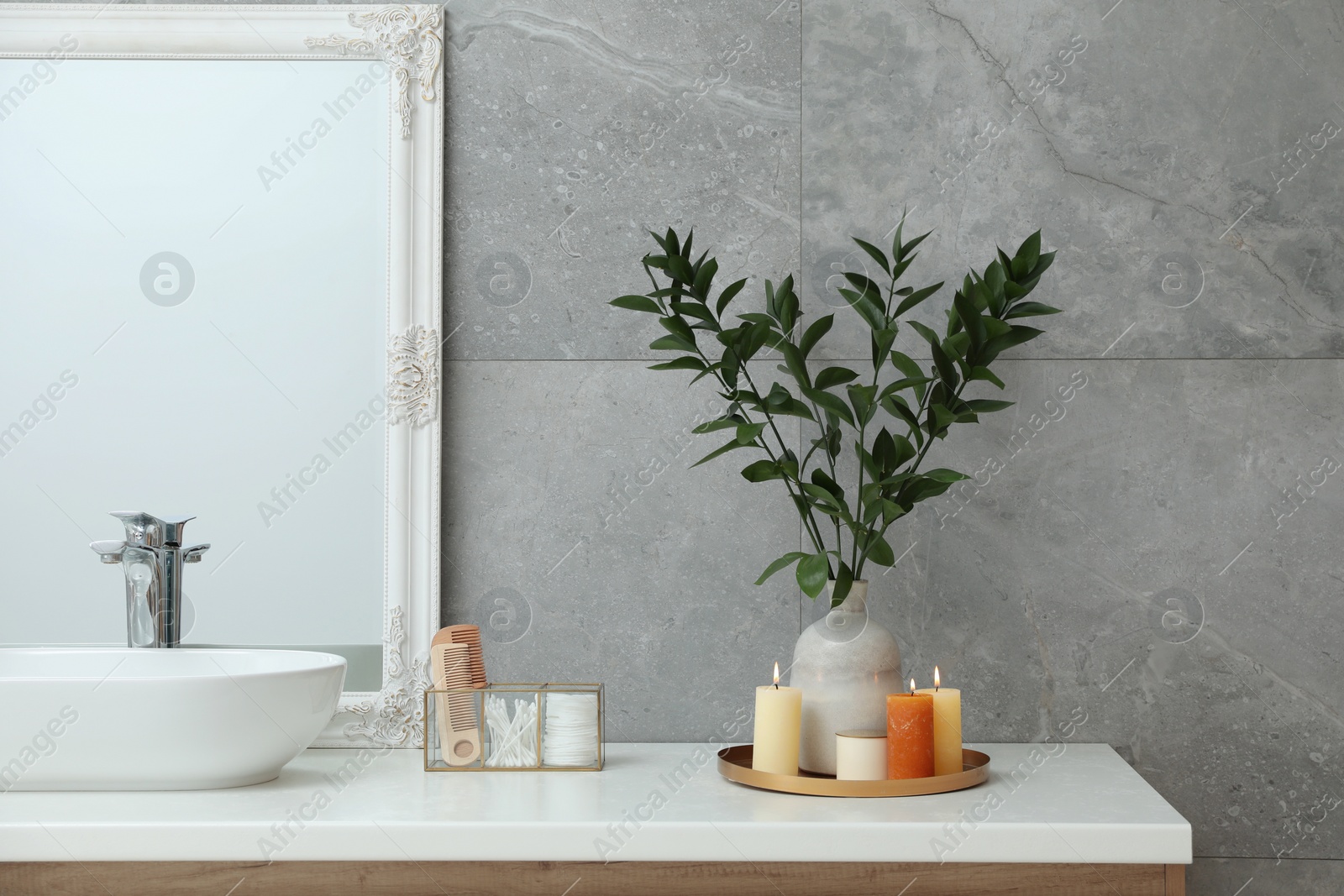 Photo of Beautiful plant in vase and burning candles near vessel sink on bathroom vanity