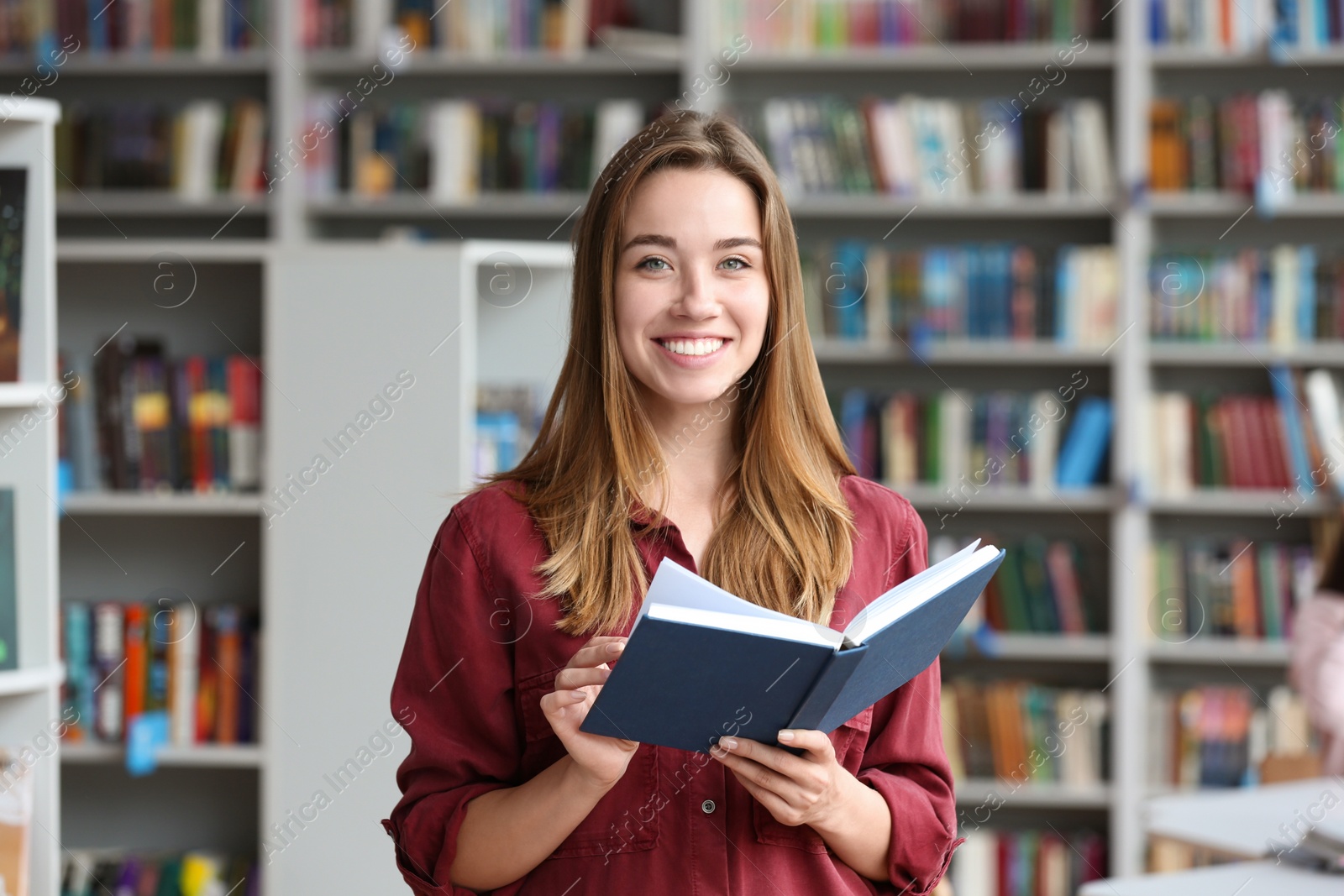 Photo of Young pretty woman with book in library