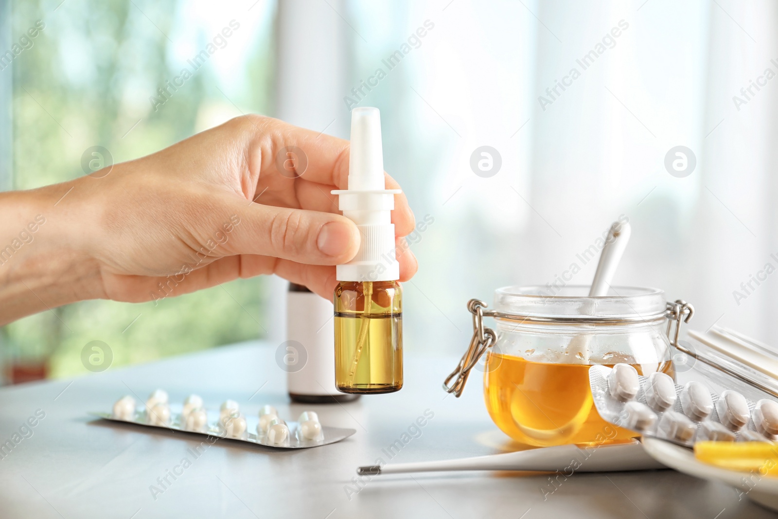 Photo of Woman holding remedy for cold over table