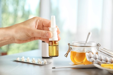 Photo of Woman holding remedy for cold over table