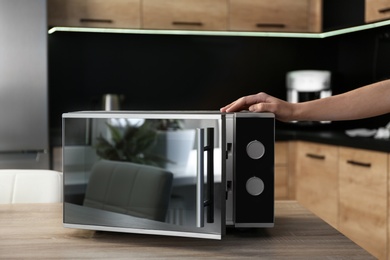 Young woman with microwave oven in kitchen