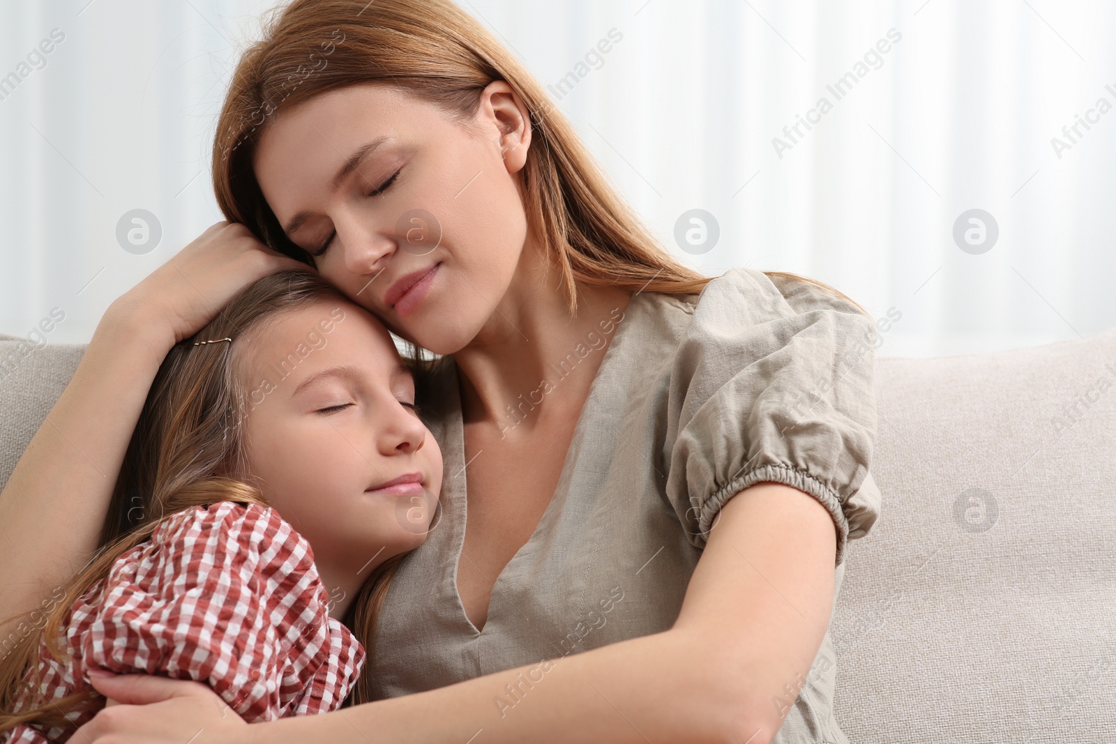 Photo of Mother and her cute daughter on sofa at home