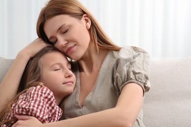 Photo of Mother and her cute daughter on sofa at home