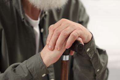 Senior man with walking cane on blurred background, closeup