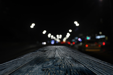 Image of Empty wooden surface and blurred view of night city