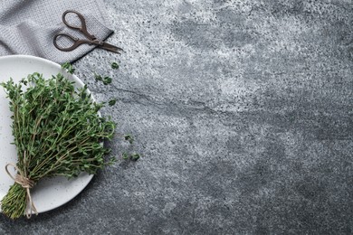 Photo of Bunch of aromatic thyme and scissors on grey table, flat lay. Space for text