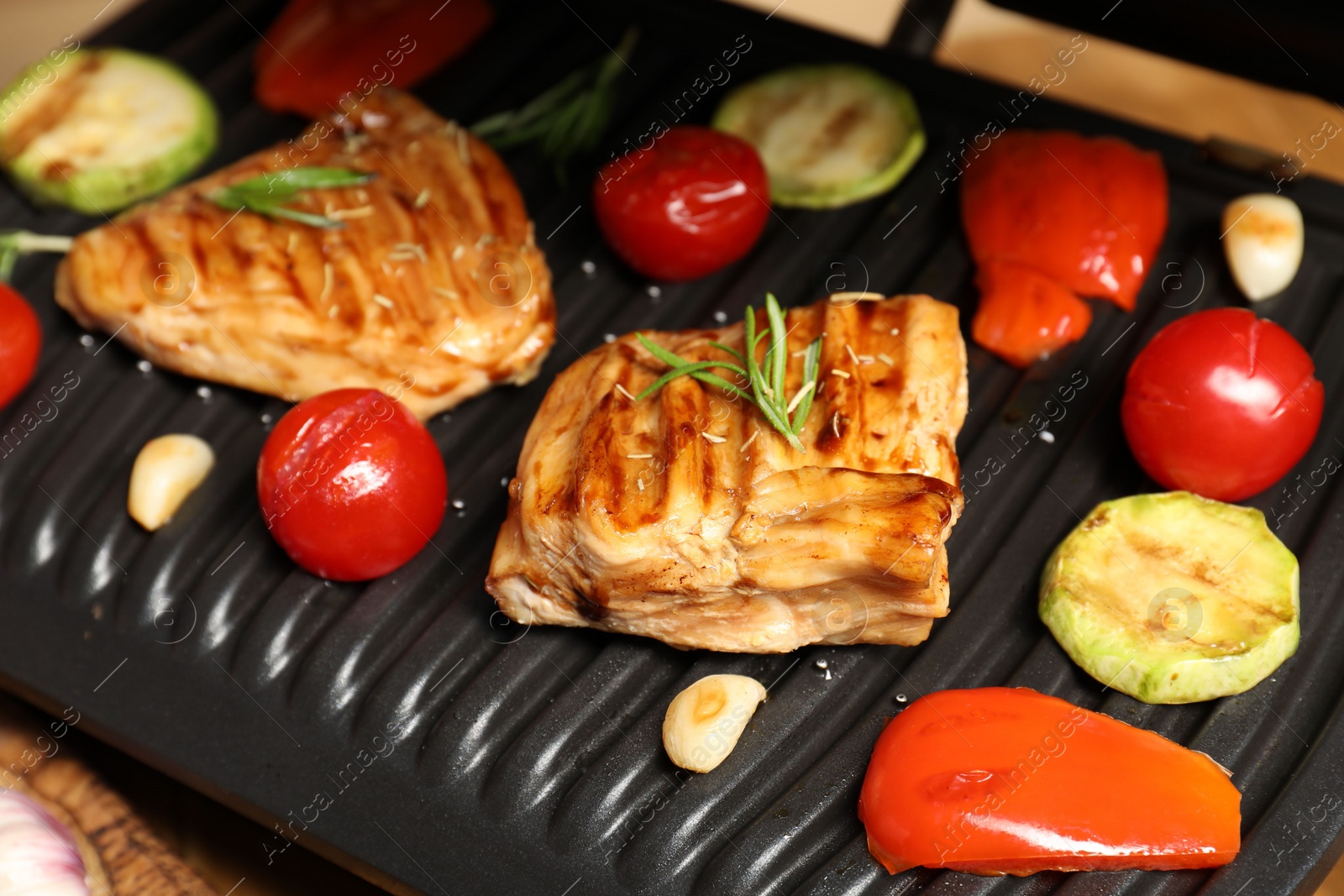 Photo of Electric grill with tasty meat, spices and vegetables on table, closeup