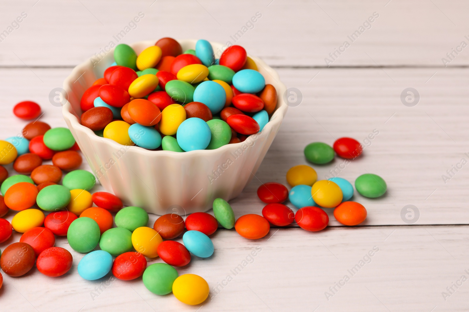 Photo of Tasty colorful candies on white wooden table, closeup