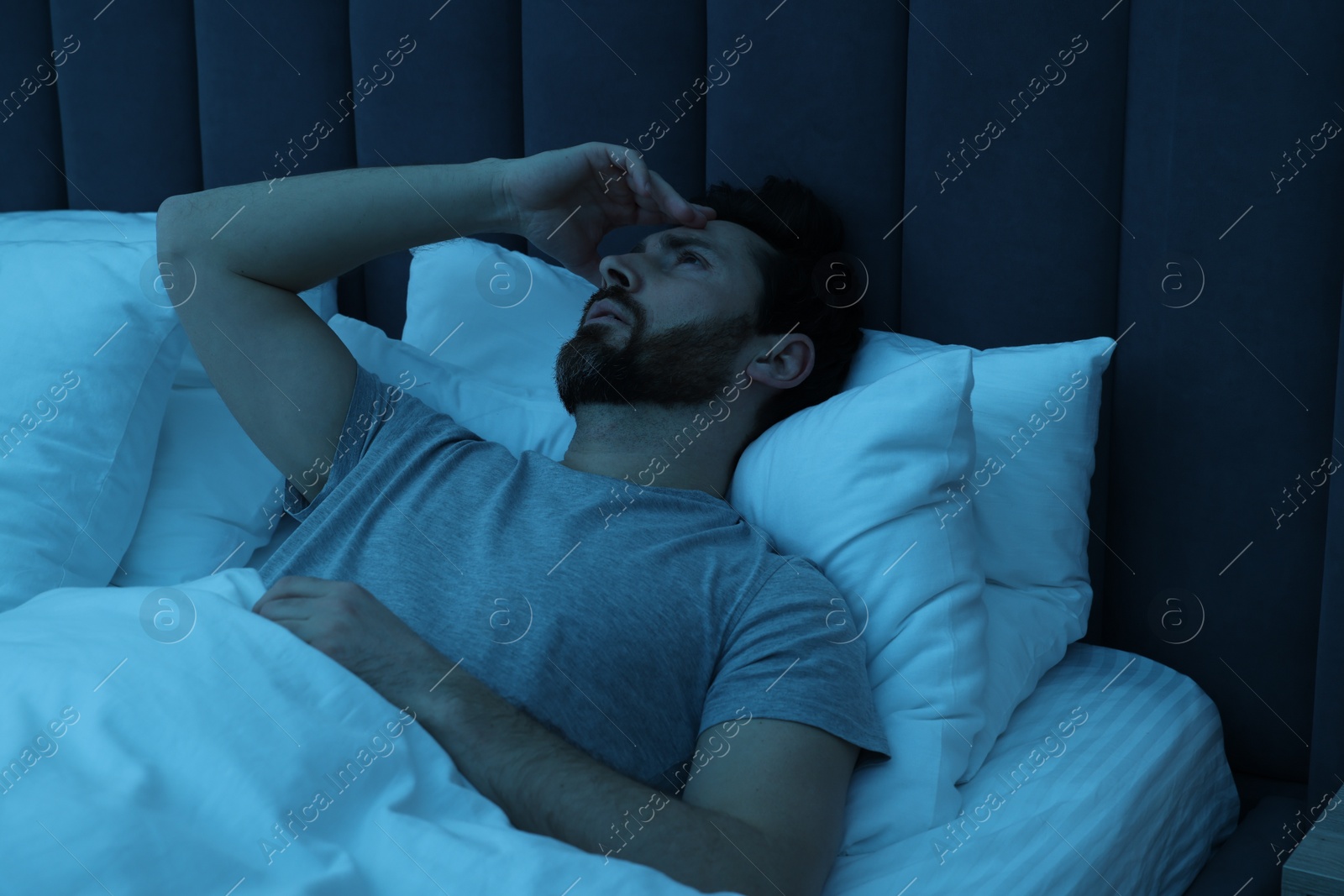 Photo of Man suffering from headache in bed at night