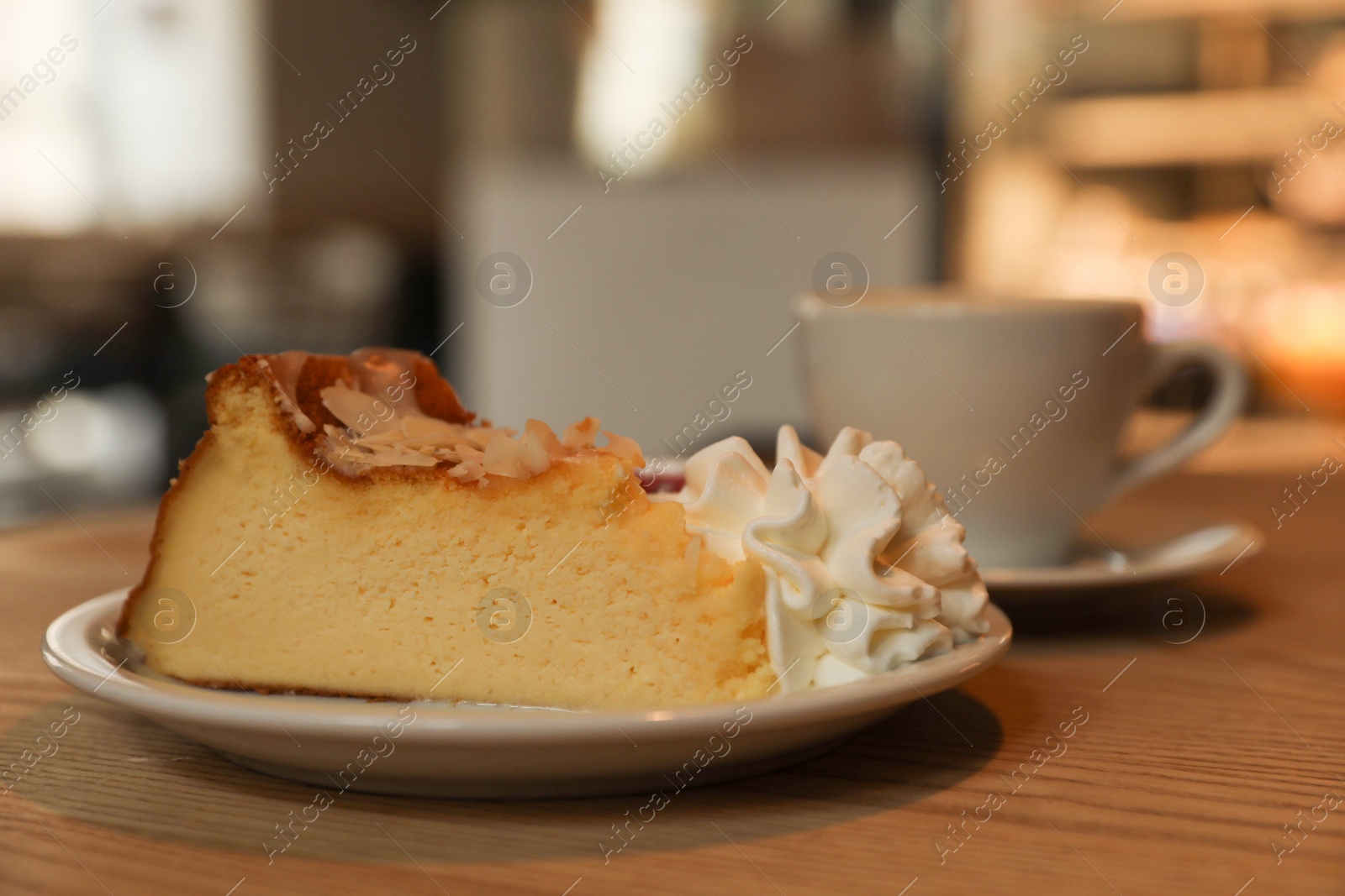 Photo of Cup of aromatic coffee and delicious dessert on wooden table in cafe, closeup