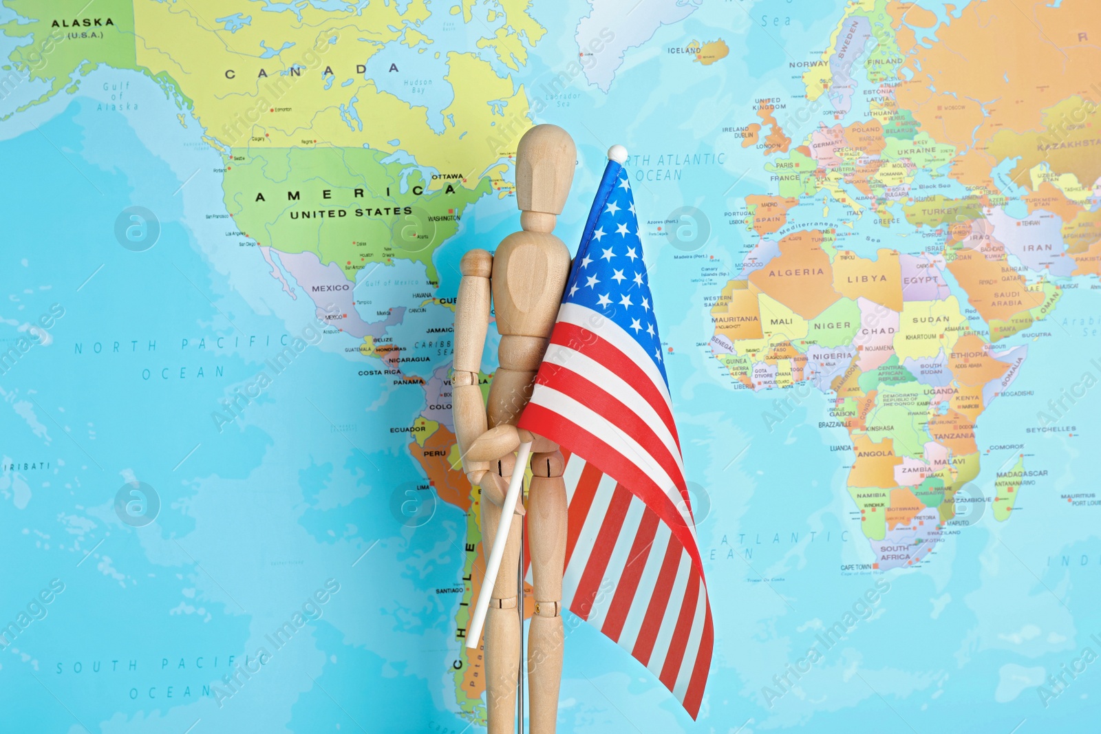 Photo of Wooden human figure with national USA flag near world map