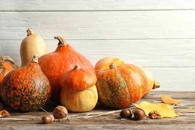 Photo of Different pumpkins on table against wooden wall. Autumn holidays