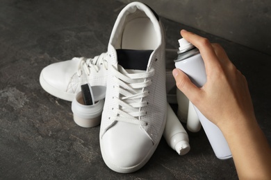 Photo of Woman cleaning stylish footwear on dark grey background, closeup. Shoe care accessories