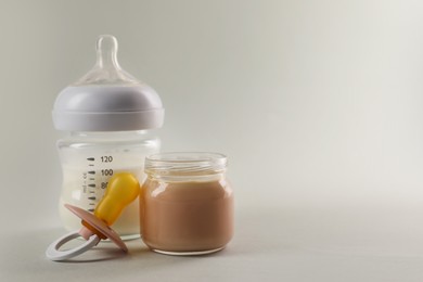 Photo of Healthy baby food, bottle of milk and pacifier on white background, space for text