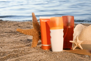 Photo of Sun protection products, hat and starfishes on sand near sea