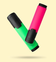Image of Pink and green markers falling on beige background