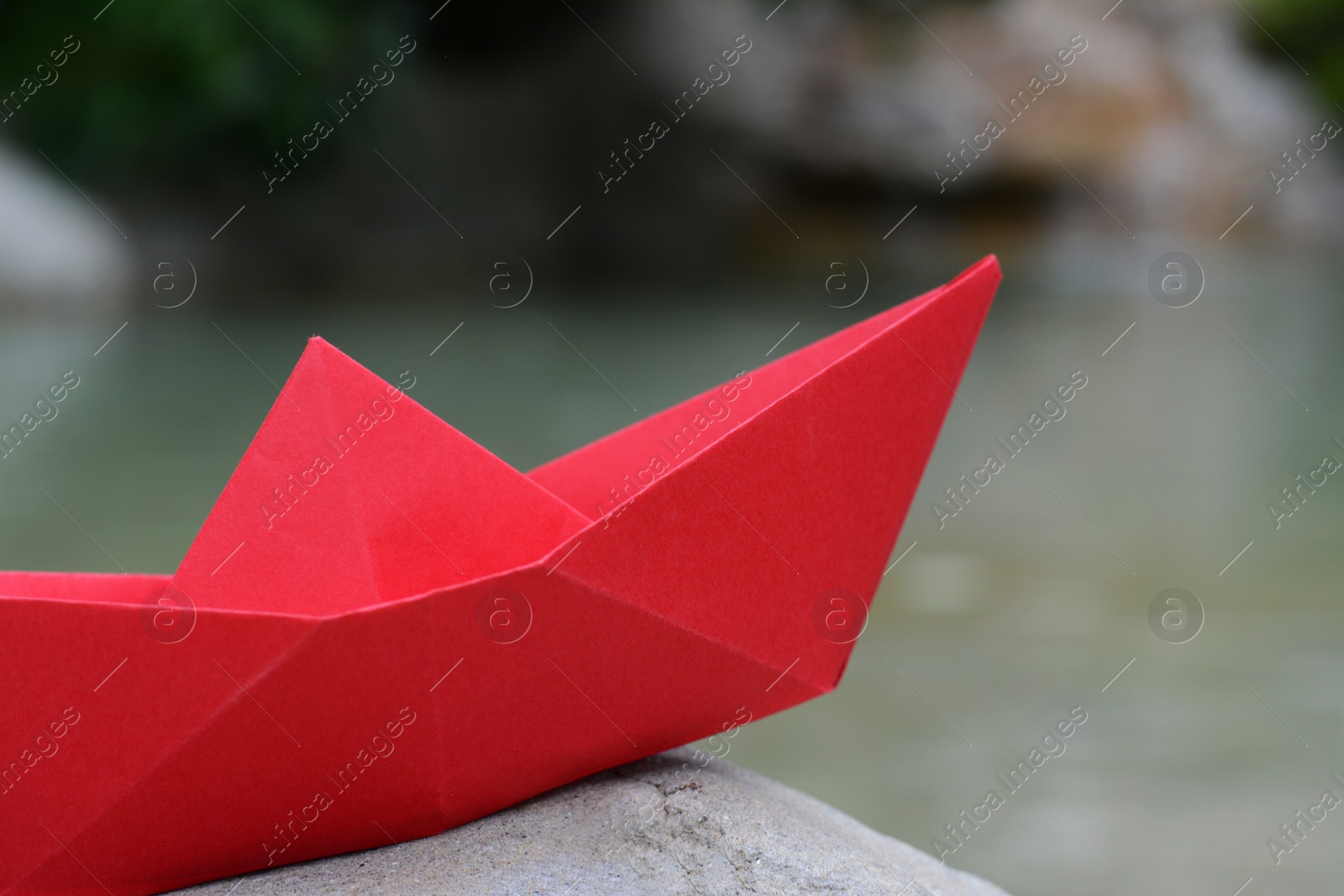 Photo of Beautiful red paper boat on stone outdoors, closeup