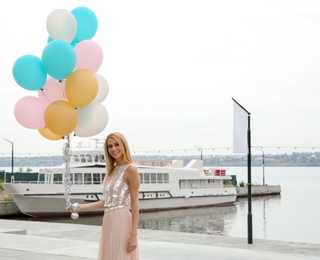 Photo of Beautiful young woman with bunch of balloons outdoors. Space for text