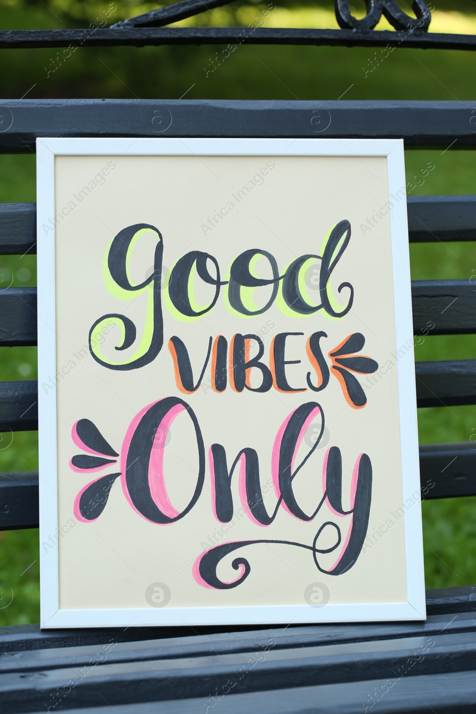 Photo of Poster with phrase Good Vibes Only on black wooden bench outdoors