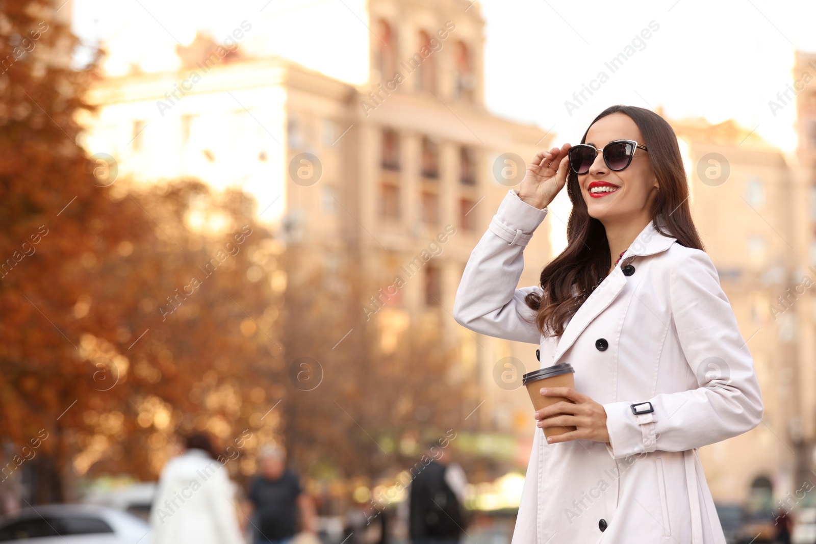 Photo of Beautiful woman with cup of coffee on city street. Autumn walk