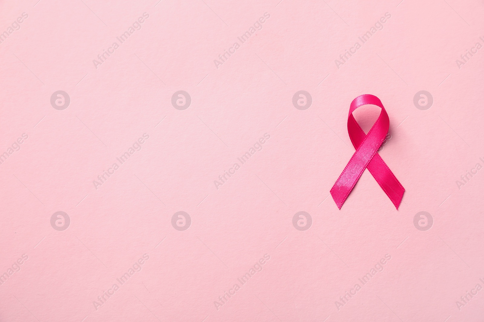 Photo of Pink ribbon on color background, top view with space for text. Breast cancer awareness concept