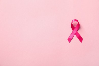 Pink ribbon on color background, top view with space for text. Breast cancer awareness concept