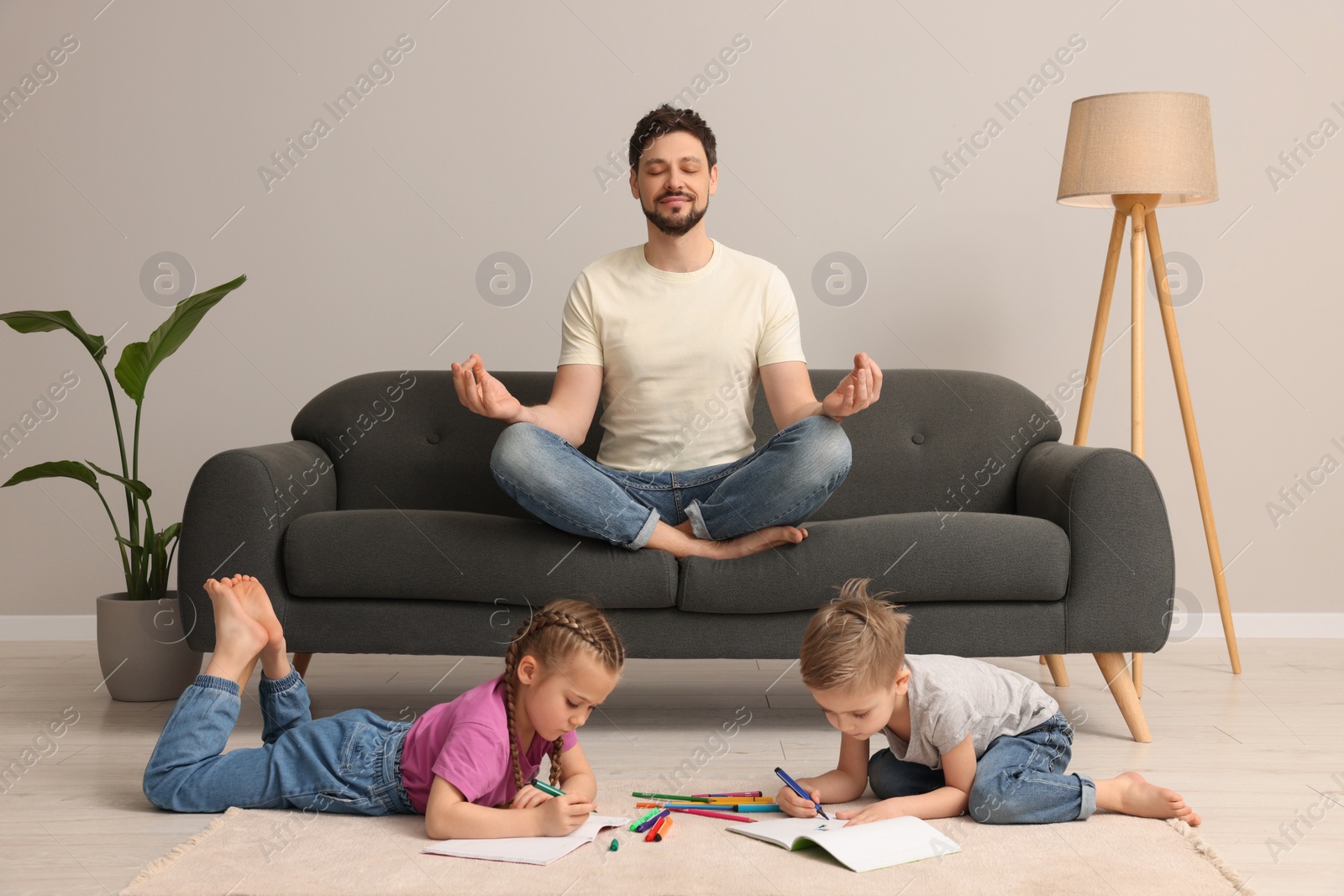 Photo of Father meditating while his children painting at home