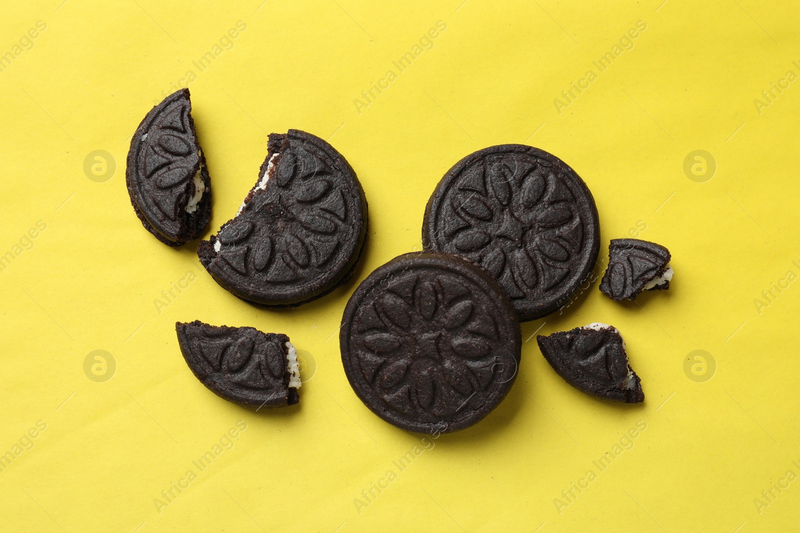 Photo of Tasty sweet sandwich cookies on yellow background, flat lay