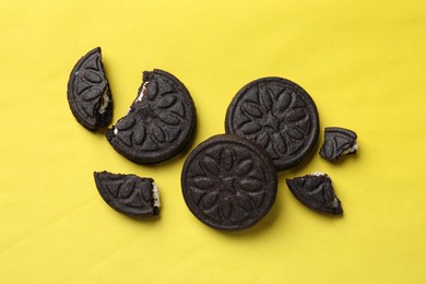 Photo of Tasty sweet sandwich cookies on yellow background, flat lay