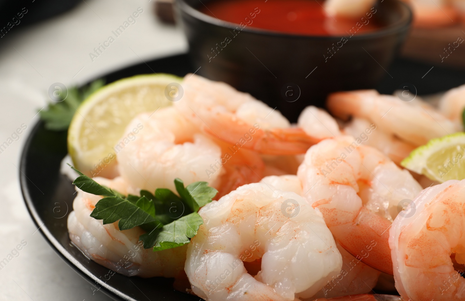 Photo of Tasty boiled shrimps with cocktail sauce, parsley and lime on light grey table, closeup