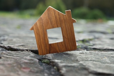Photo of Wooden house model between cracks on stone road. Earthquake disaster