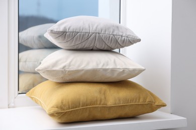 Photo of Stack of soft pillows on window sill indoors