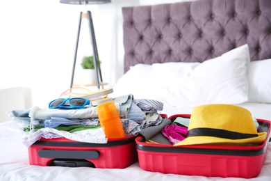 Photo of Open suitcase with different clothes and accessories for summer journey on bed