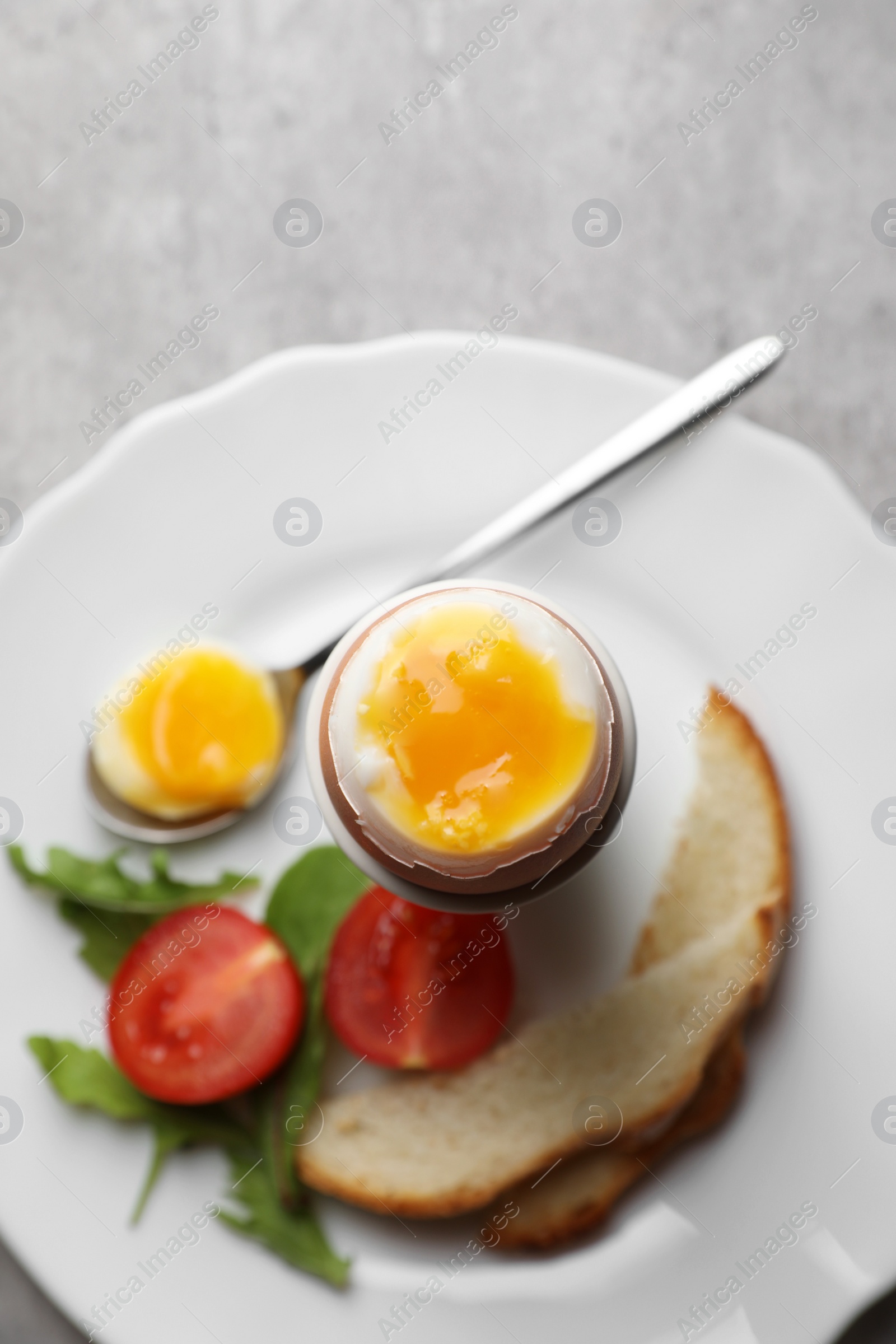 Photo of Breakfast with soft boiled egg on grey table, top view. Space for text