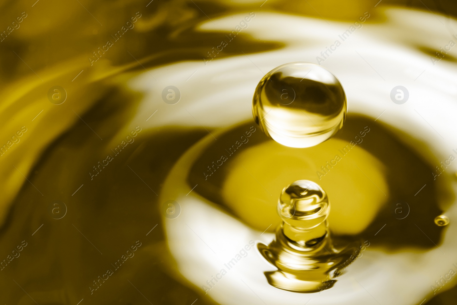 Image of Splash of golden oily liquid with drops as background, closeup. Space for text